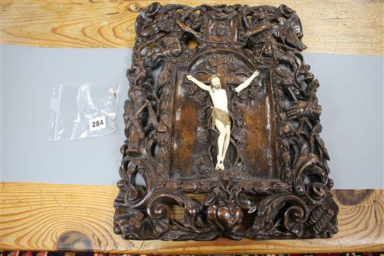 A 19th century European carved walnut and ivory crucifix, the ivory Corpus Christi on a pierced plaque decorated with angels, scrolls a